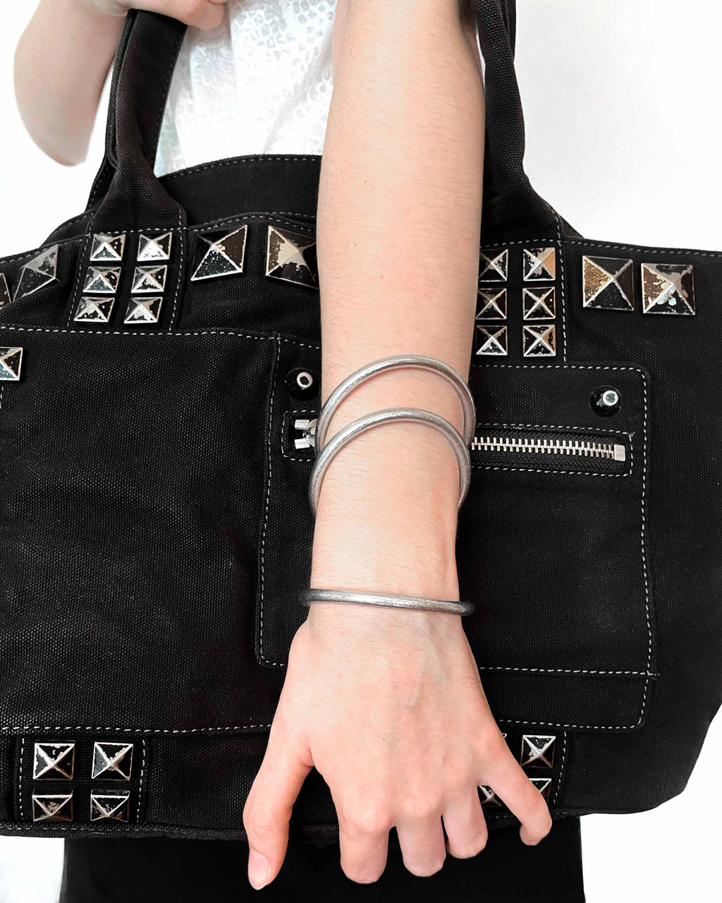 Pulseras budistas Kumlai en plata clásica, estilo grueso, usadas con un bolso rock negro.