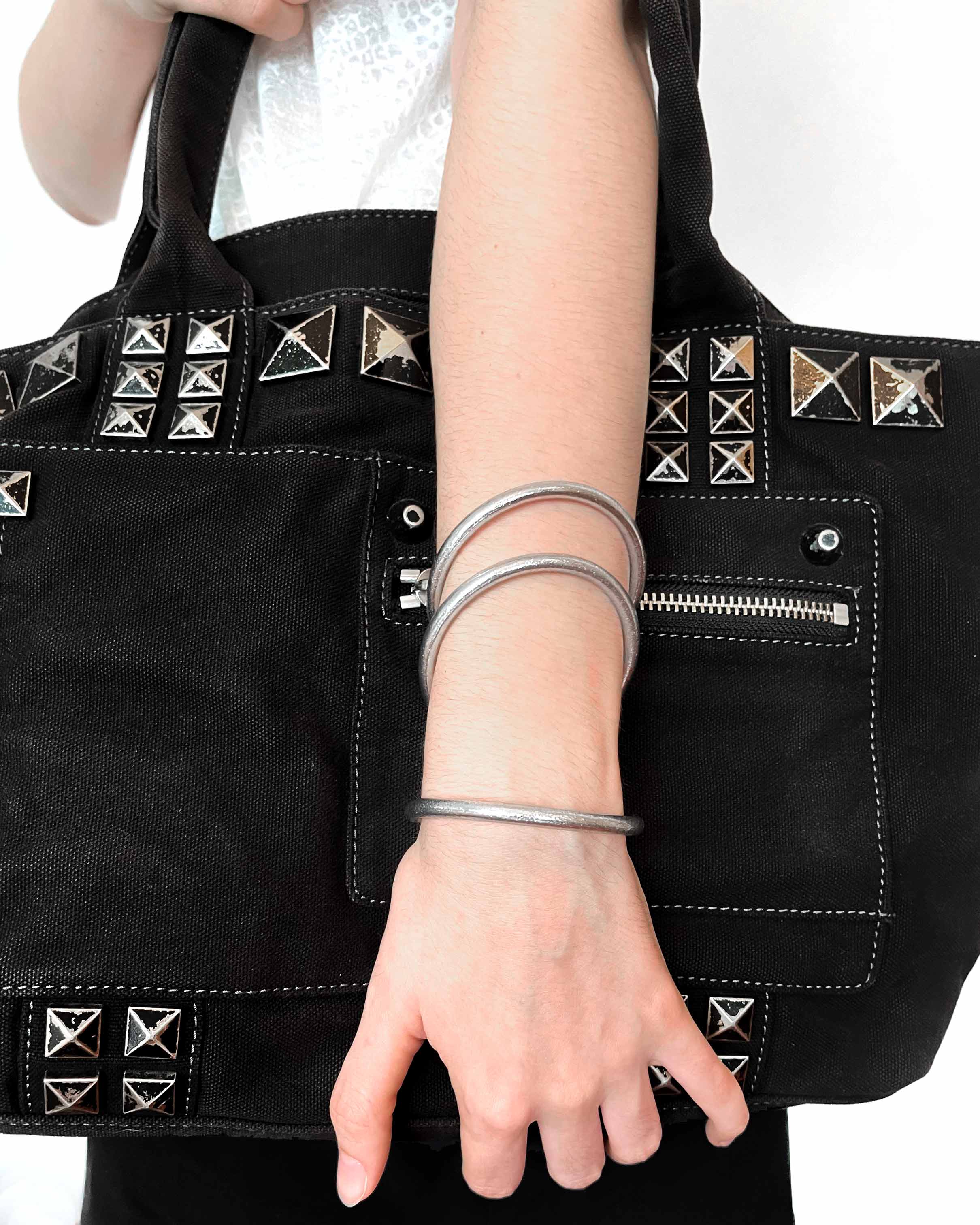 Pulseras budistas Kumlai en plata clásica, estilo grueso, usadas con un bolso rock negro.