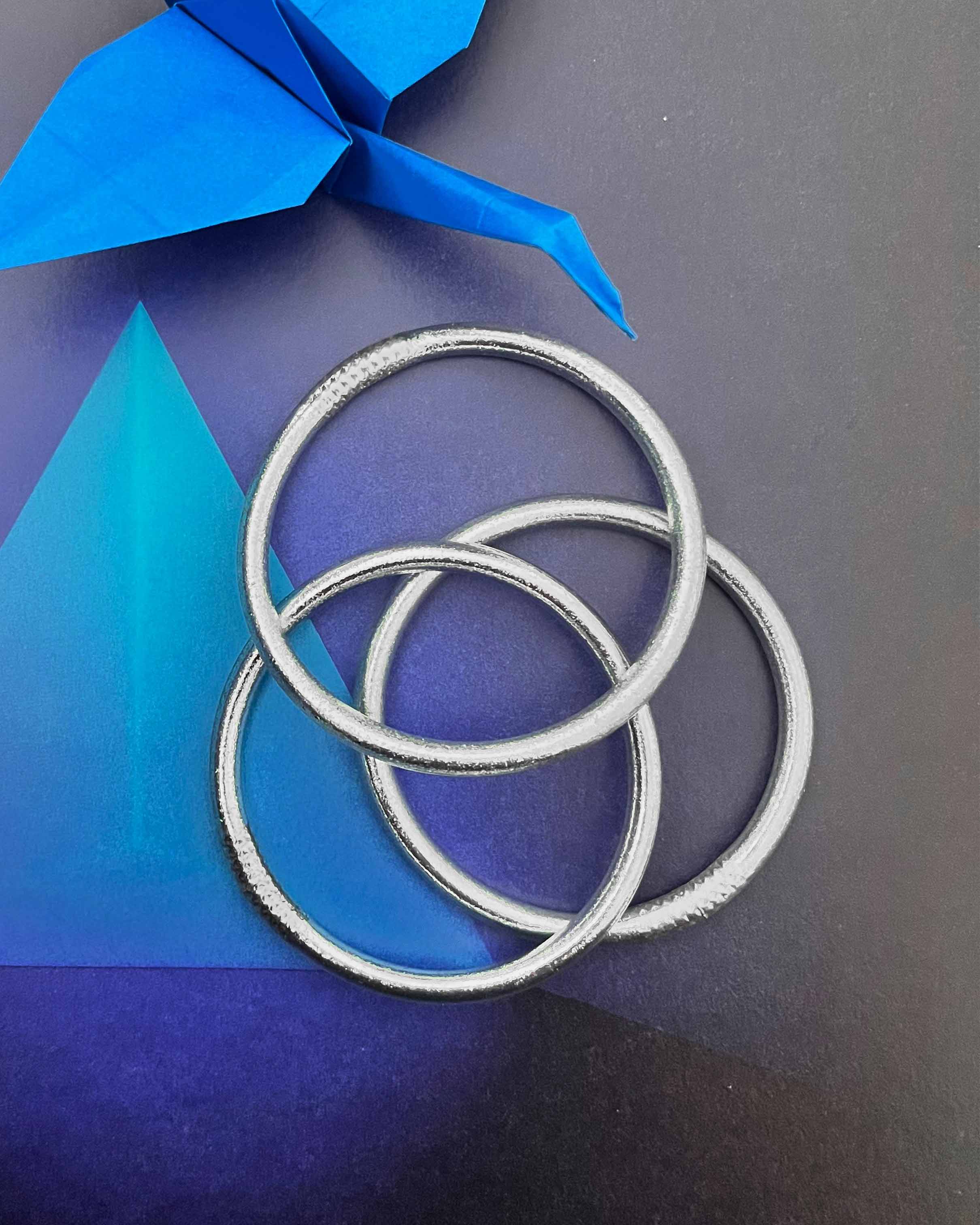 Pulseras budistas Kumlai en plata clásica, estilo grueso, junto a un origami.