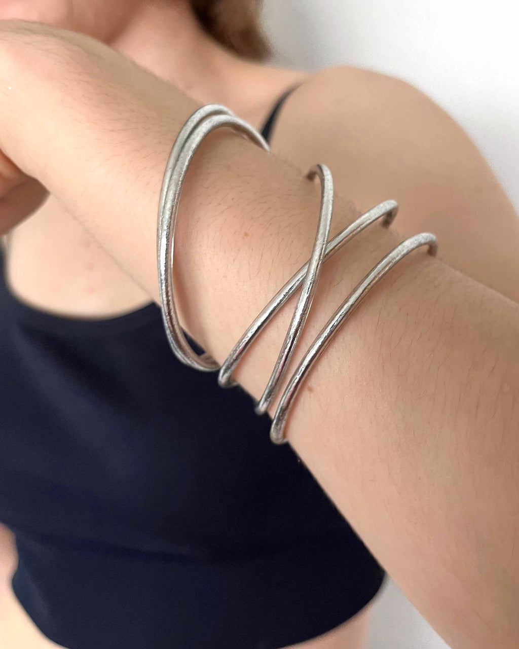 Pulseras budistas Kumlai en plata clásica, estilo fino, usadas con un crop top azul marino.
