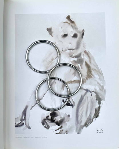 Joncs bouddhistes Kumlaï épais en argent classique, posés sur une illustration figurant un singe.