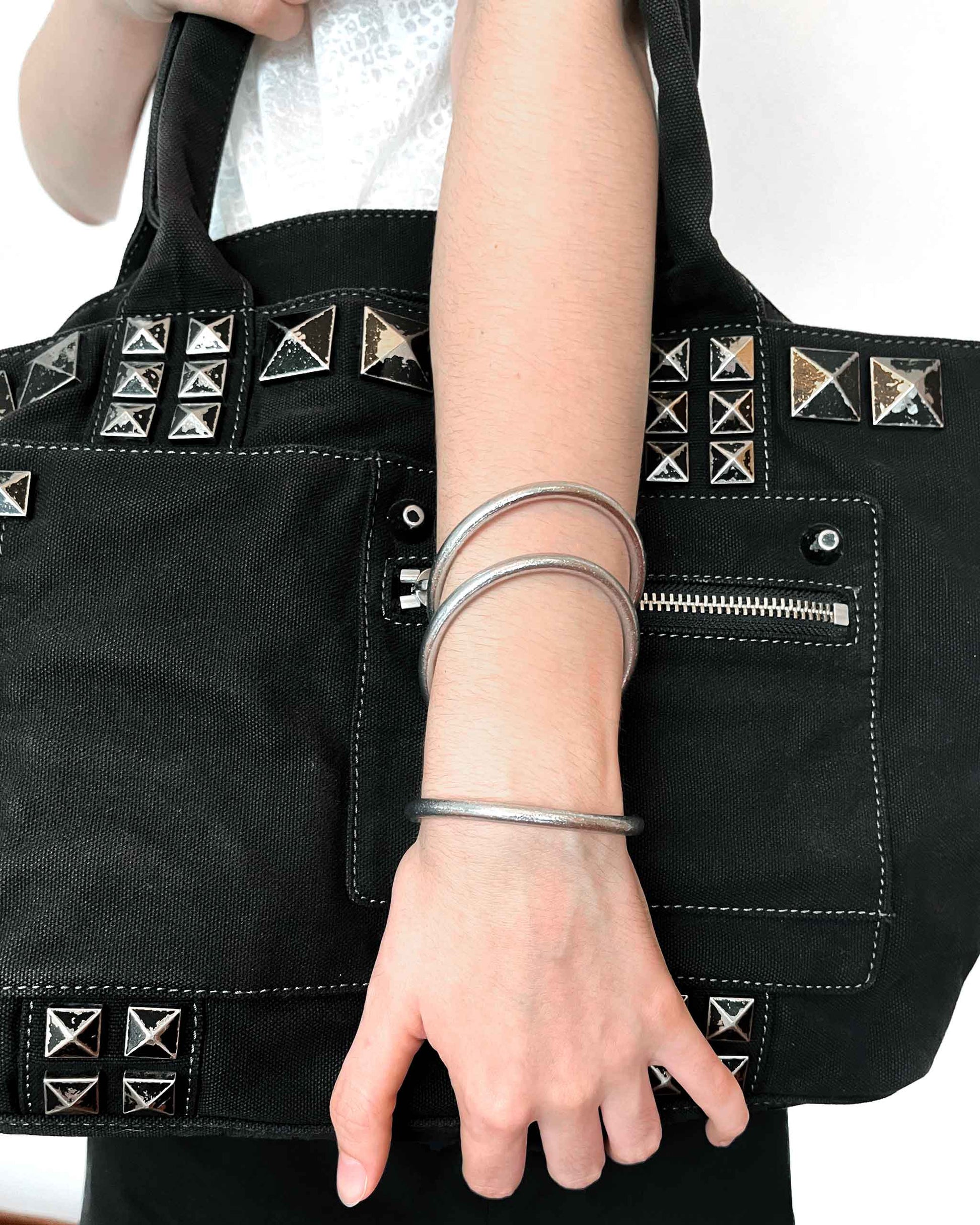 Joncs bouddhistes Kumlaï épais en argent classique, portés avec un sac rock noir et argent.