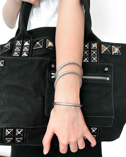 Joncs bouddhistes Kumlaï épais en argent classique, portés avec un sac rock noir et argent.