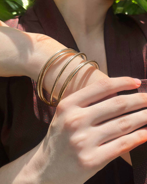 Kumlai Buddhist bangles in champagne gold, slim style, worn with a burgundy kimono.