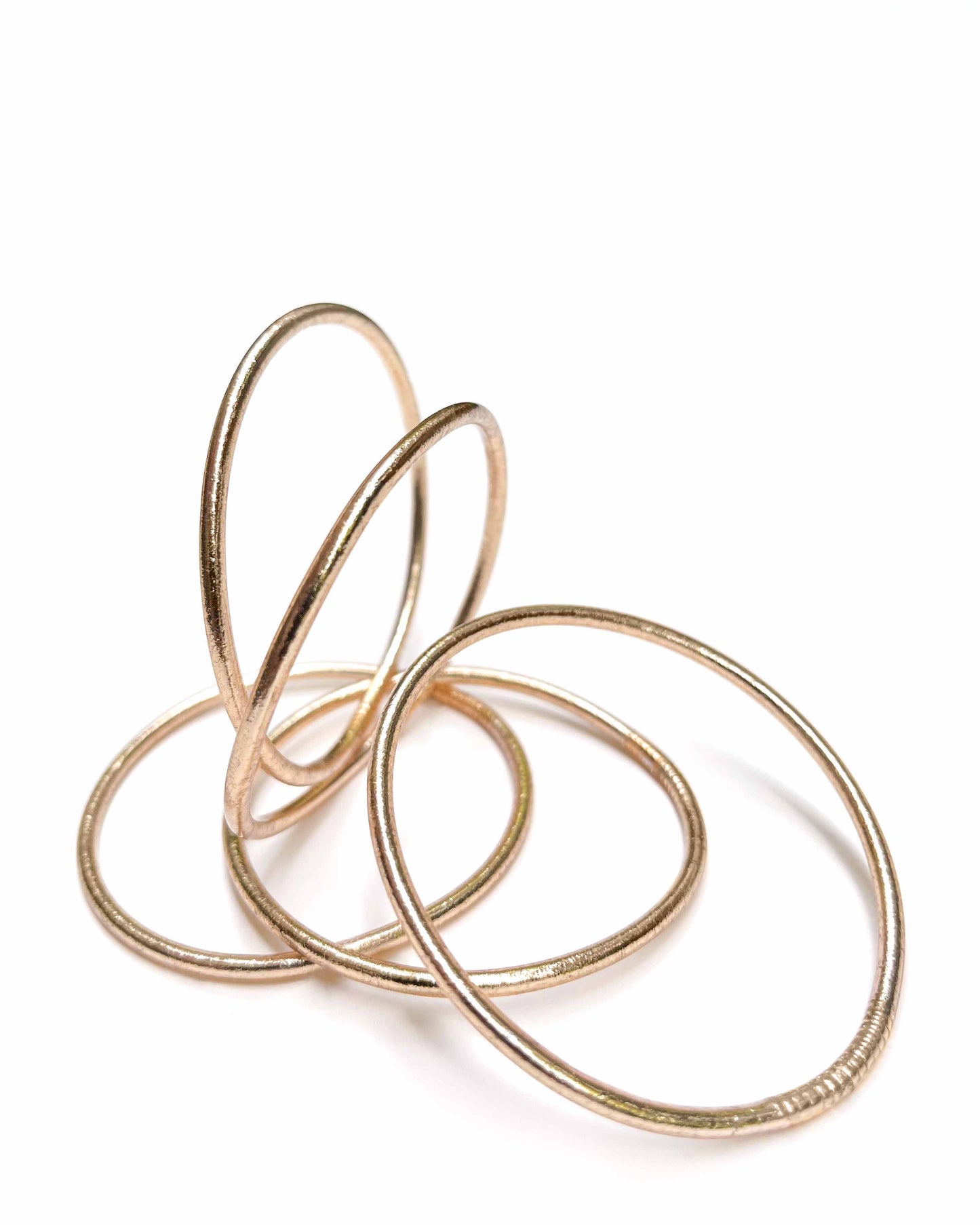 Thin Kumlai Buddhist bangles in Champagne Gold on a white background.
