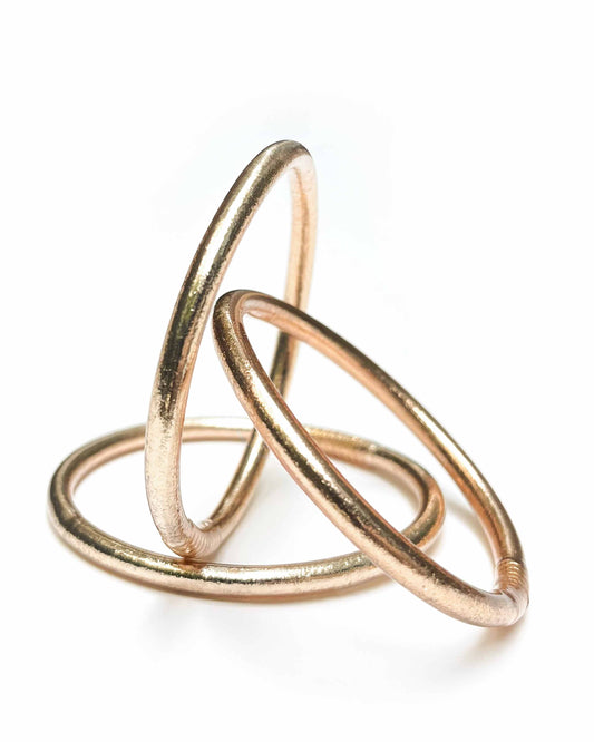 Chunky Kumlai Buddhist bangles in Champagne Gold on a white background.