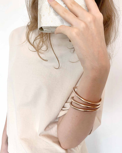 Chunky Kumlai Buddhist bangles in champagne gold, worn with a light top and a Japanese evening clutch.