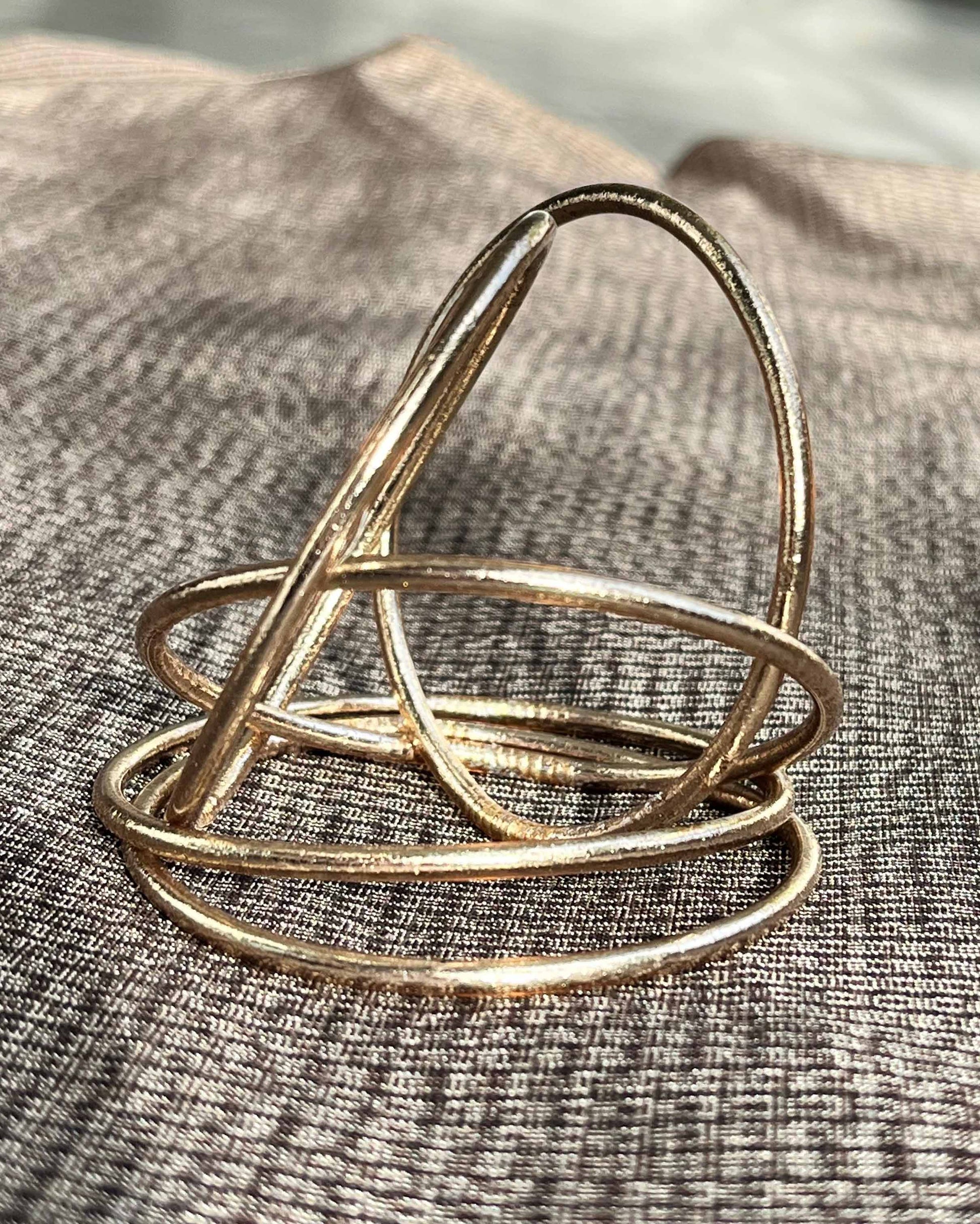 Slim Kumlai Buddhist bangles in champagne gold, placed on Japanese kimono fabric.