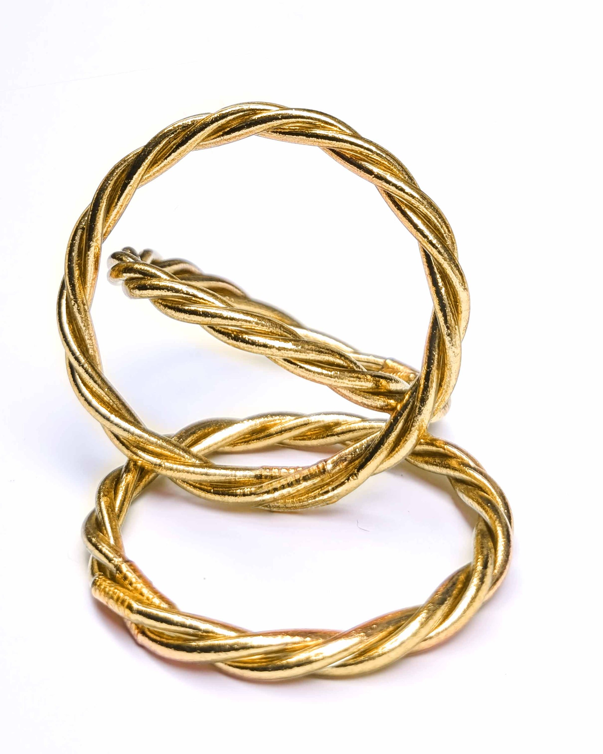 Trinity Kumlai Buddhist bangles in classic gold, on a neutral background.