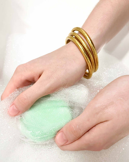 Chunky Kumlai Buddhist bangles in classic gold, worn in soapy water.