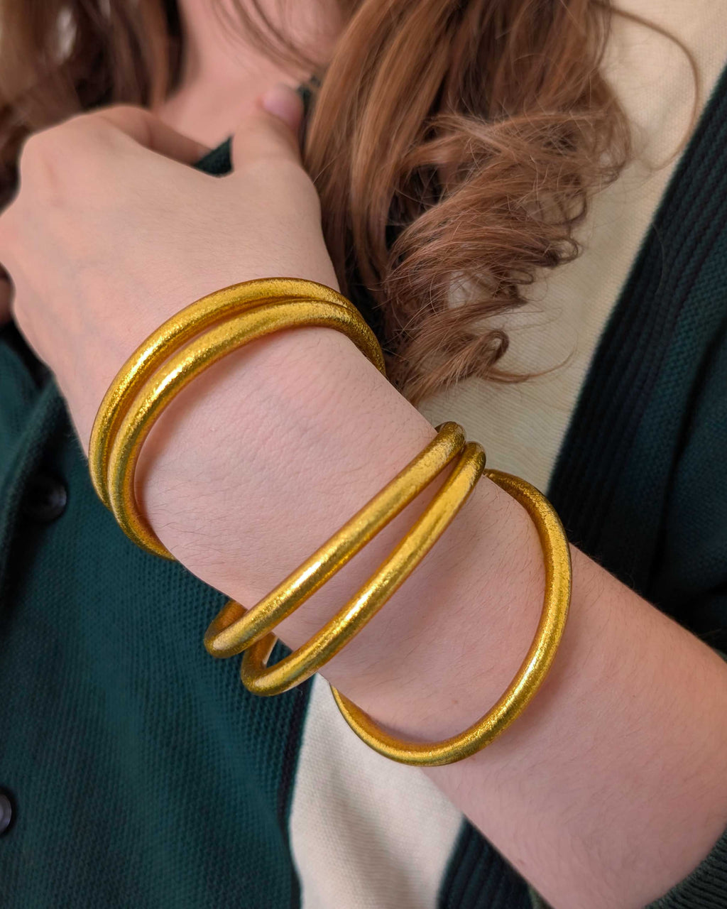 Kumlai Buddhist bangles in rich gold, chunky style, worn with a dark green cardigan. (2)