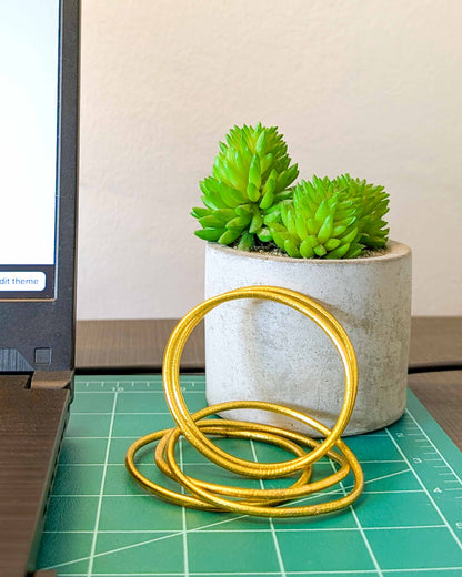 Slim Kumlai Buddhist bangles in rich gold, placed on my desk.