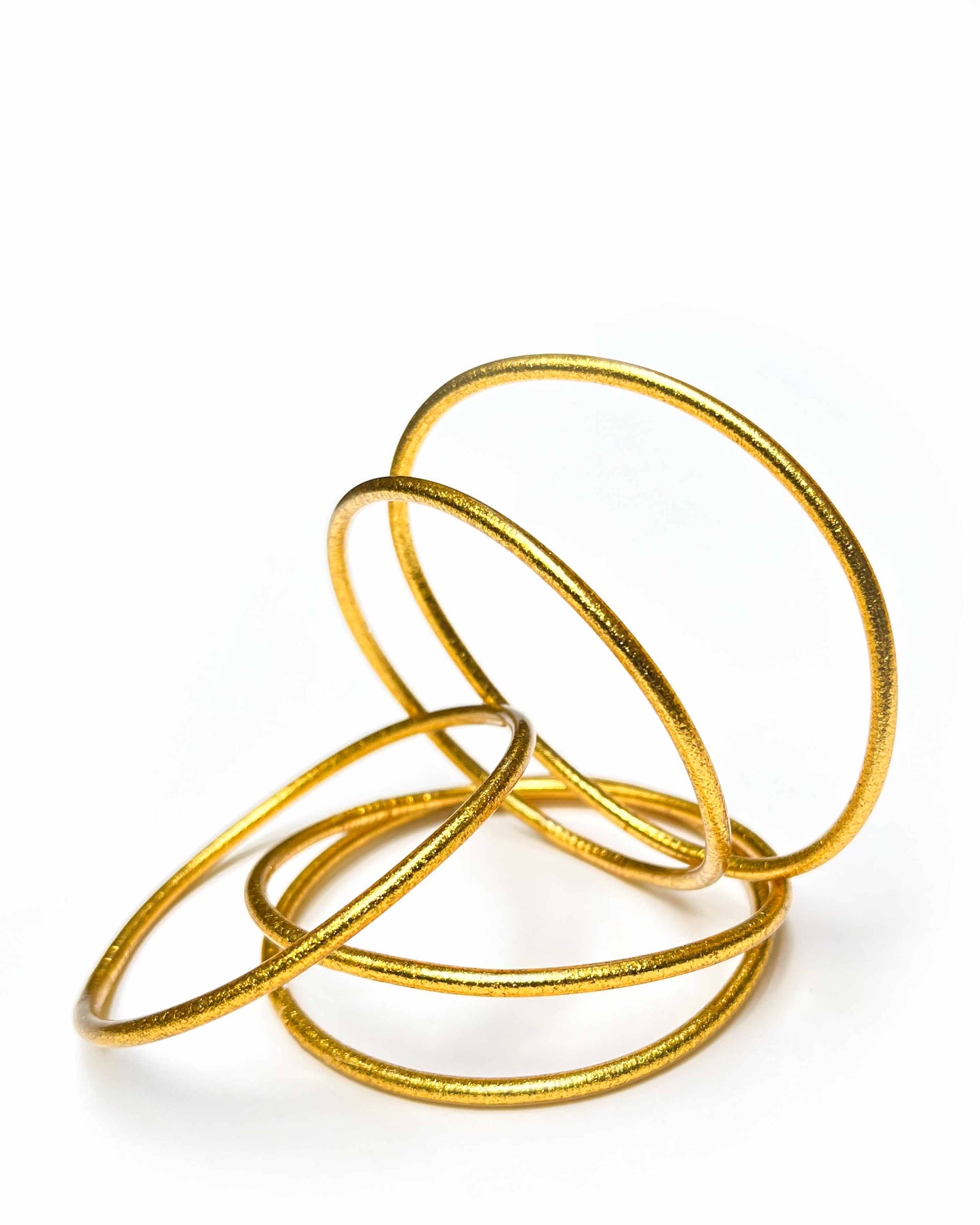 Thin Kumlai Buddhist bangles in Rich Gold on a white background.