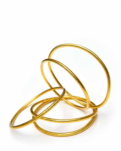 Thin Kumlai Buddhist bangles in Rich Gold on a white background.