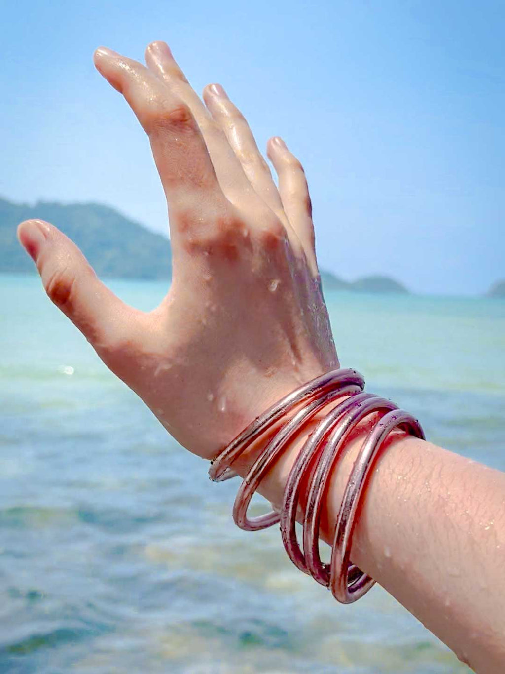 Kumlai Buddhist bangles in rose gold, chunky style, worn at the beach.