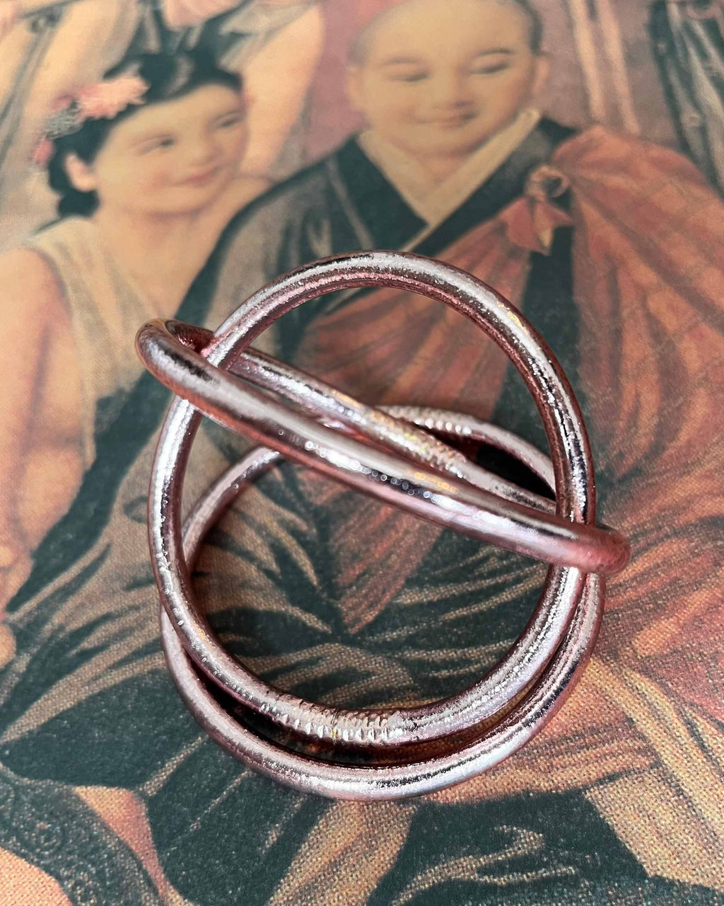 Pulseras budistas Kumlai en oro rosa, estilo grueso, sobre un póster vintage.