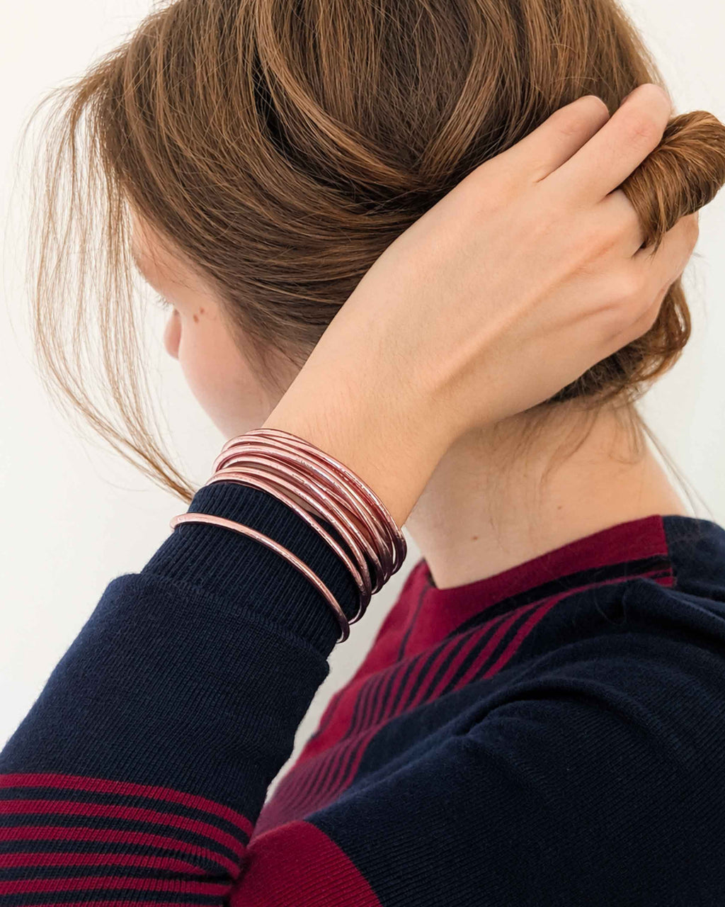 Kumlai Buddhist bangles in rose gold, slim style, worn with a navy blue and burgundy knit sweater. (2)