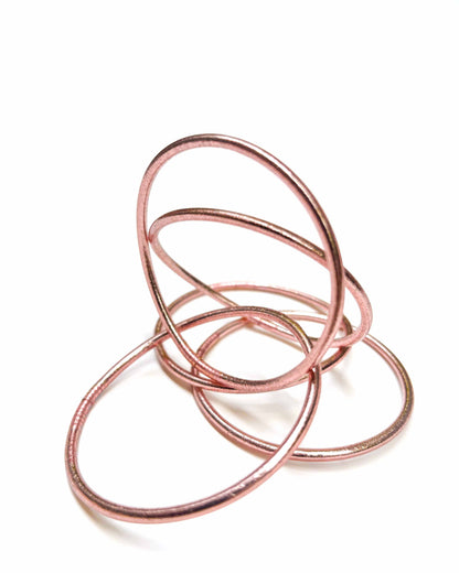 Thin Kumlai Buddhist bangles in Rose Gold on a white background.